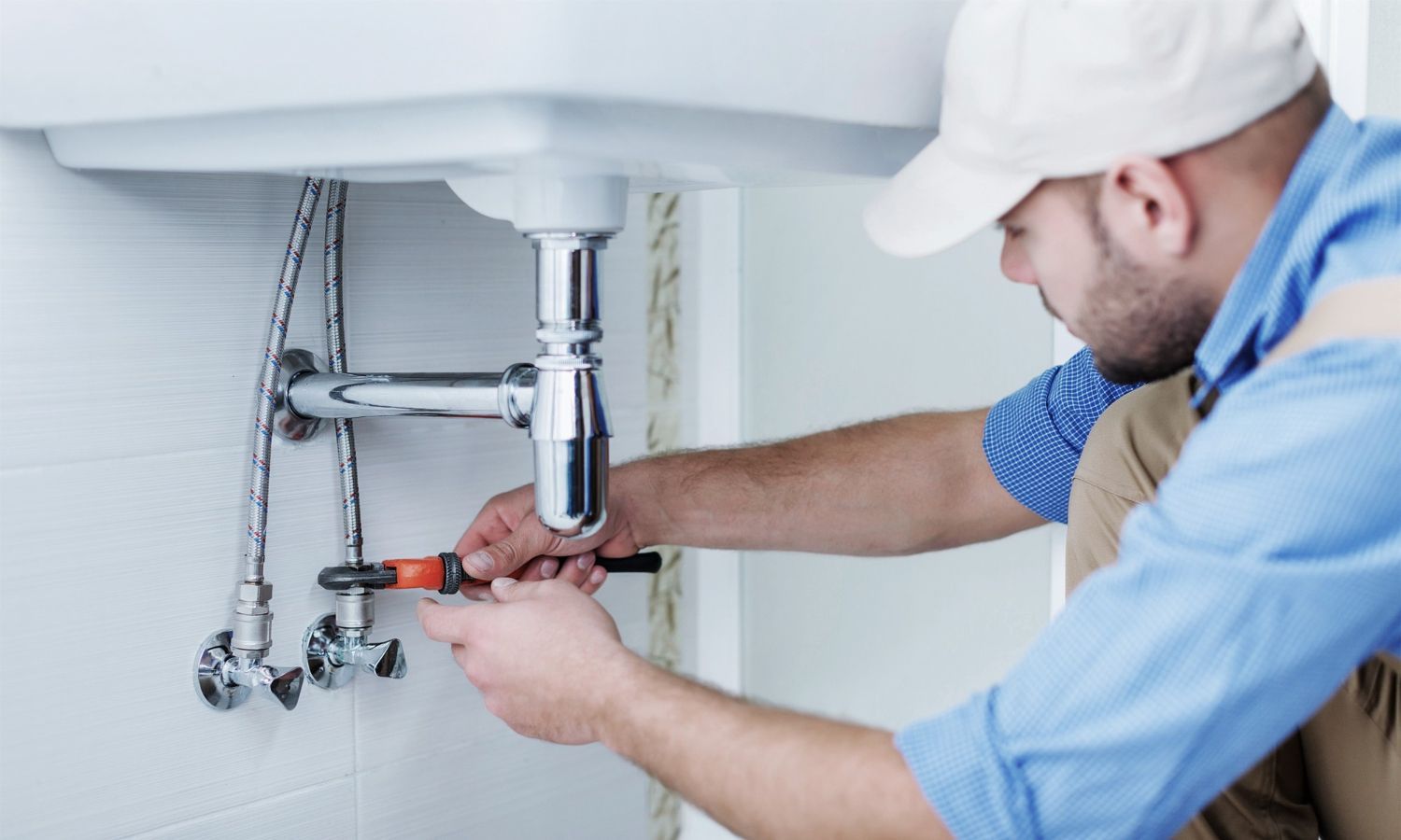 A plumber is fixing a sink with a screwdriver.