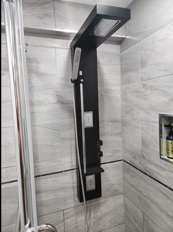 A bathroom with a shower head and a soap shelf.