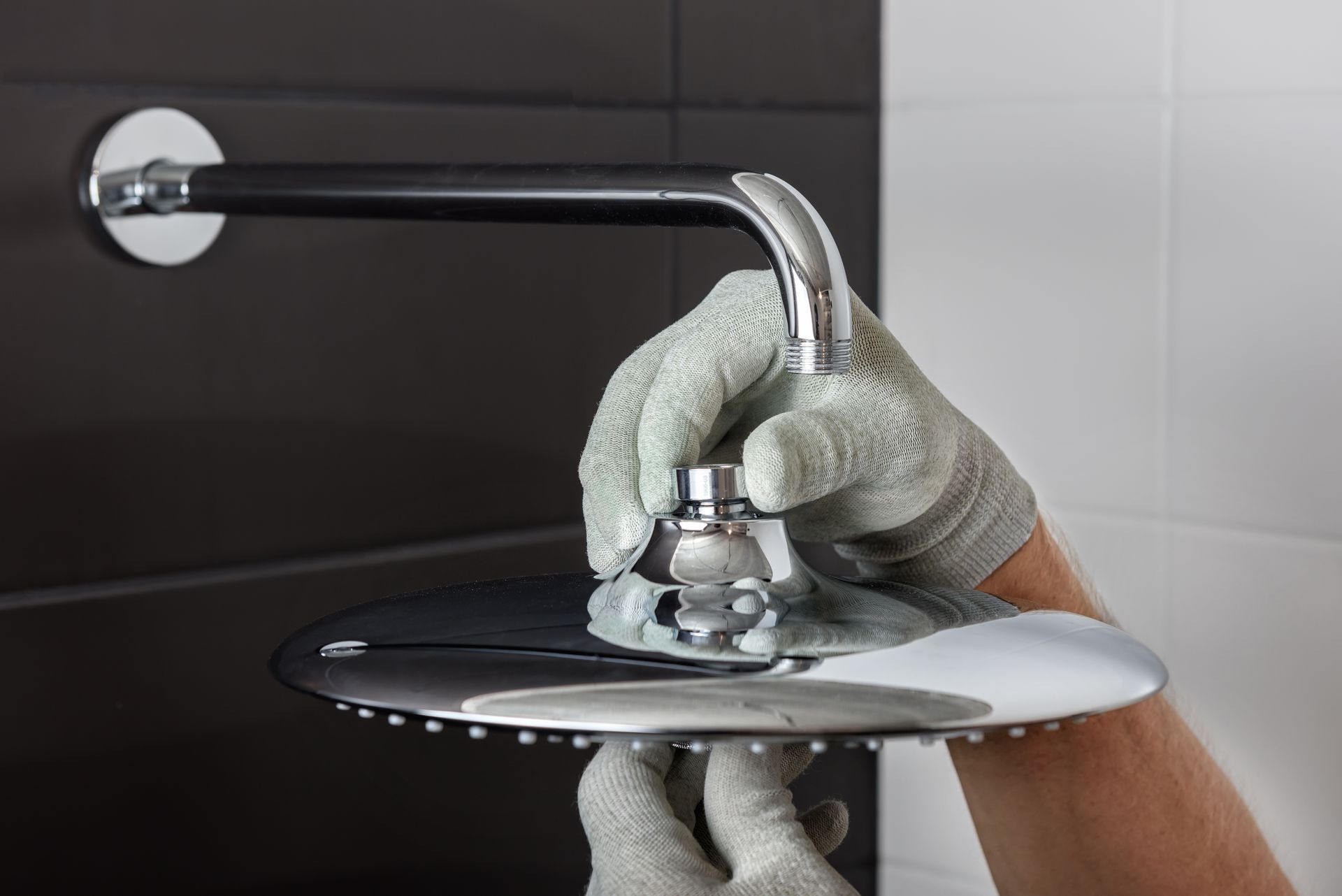 a person is fixing a shower head in a bathroom .