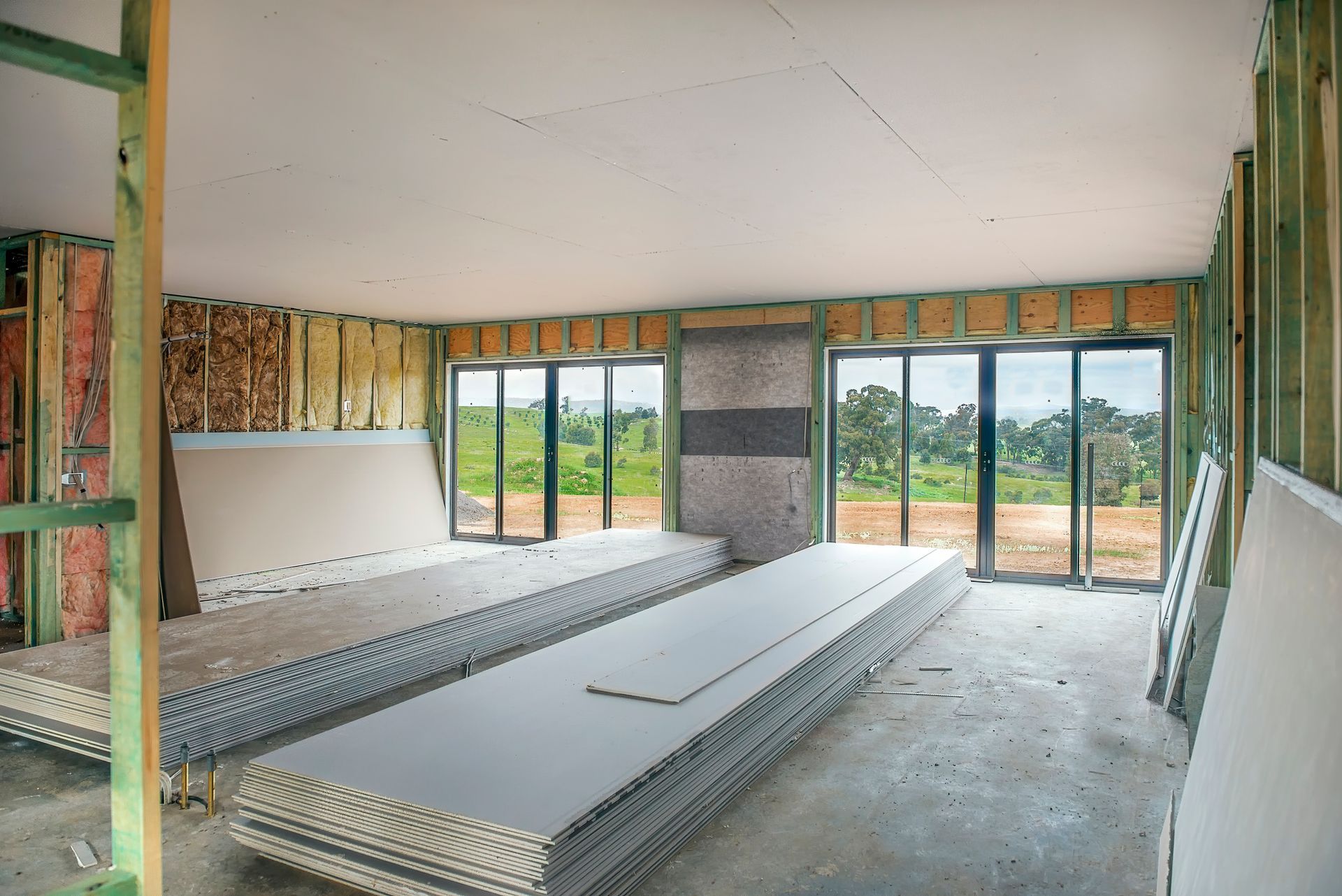 A large room with a lot of windows and a stack of drywall.