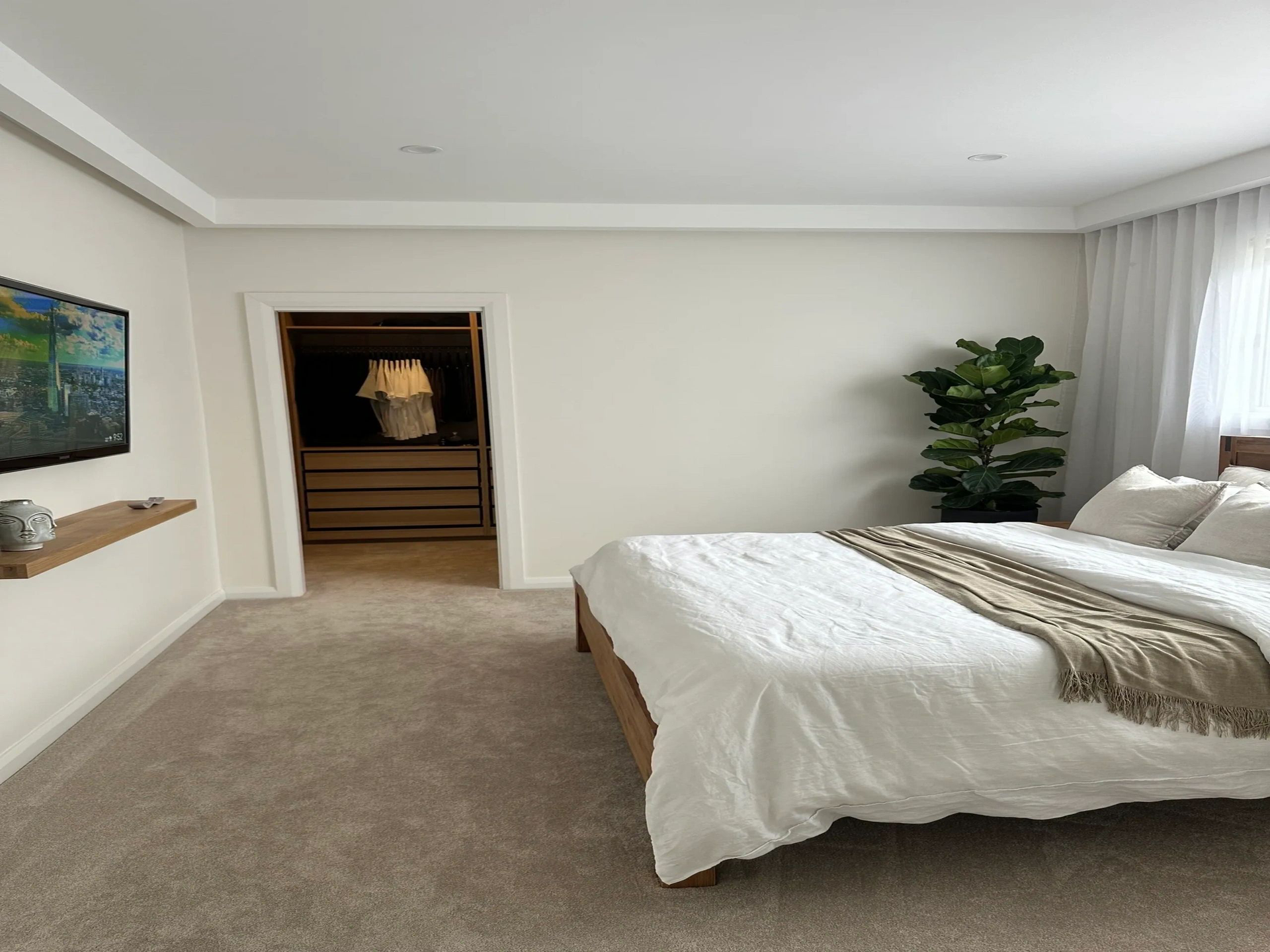 A bedroom with a large bed and a flat screen tv on the wall.