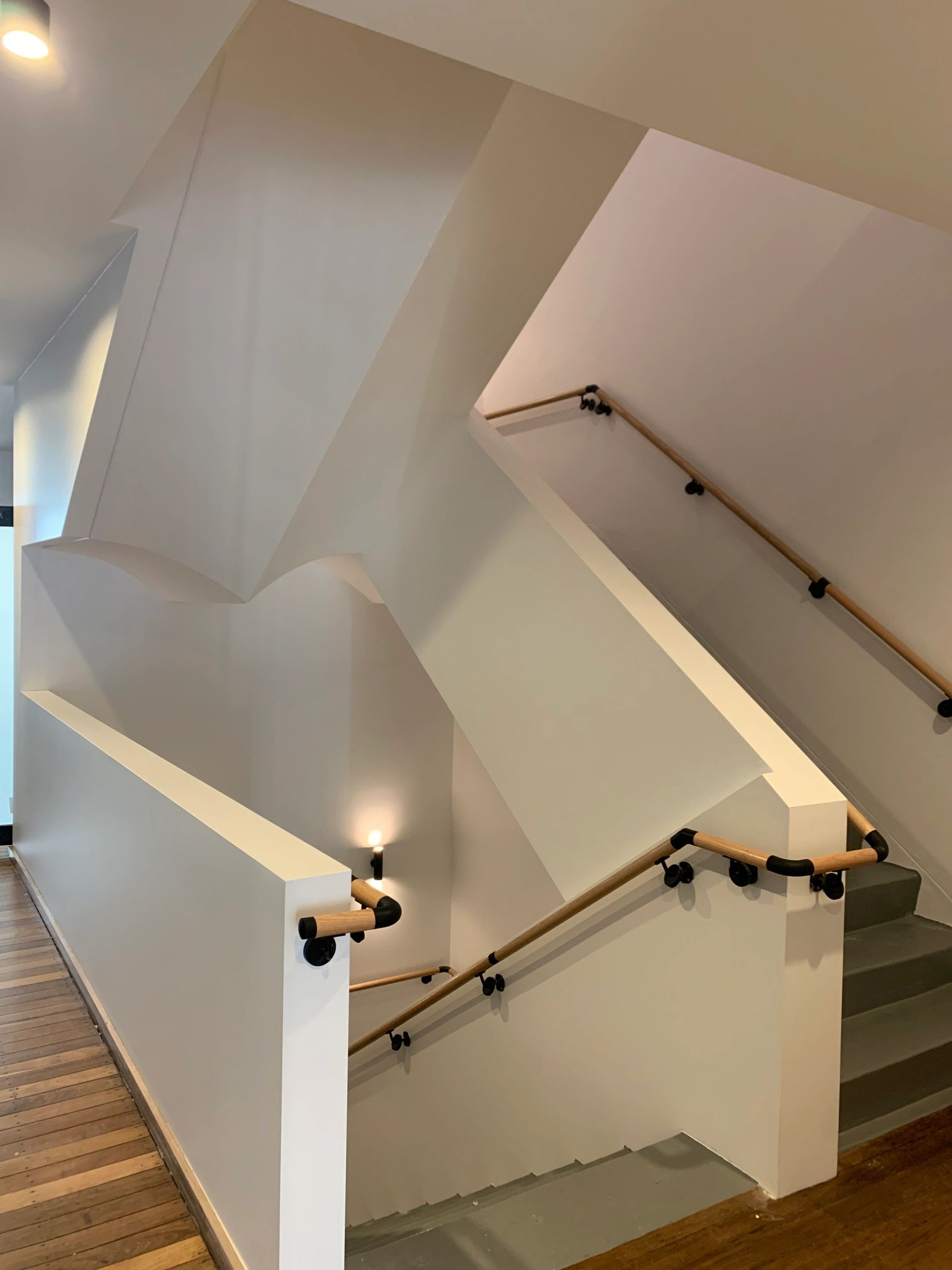 A staircase with a wooden railing and a white wall