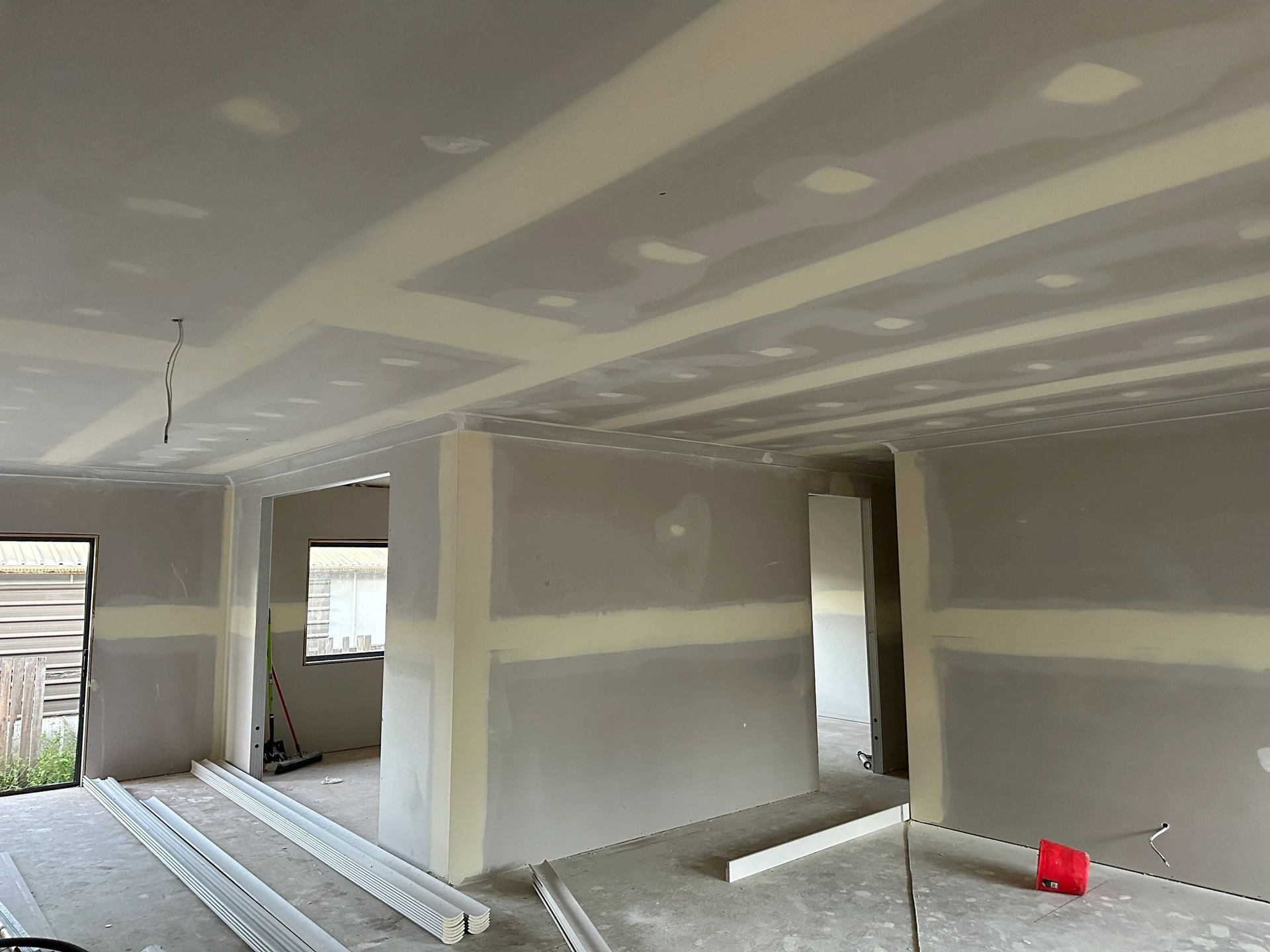 A room with a ceiling that is being built and a red bucket on the floor.