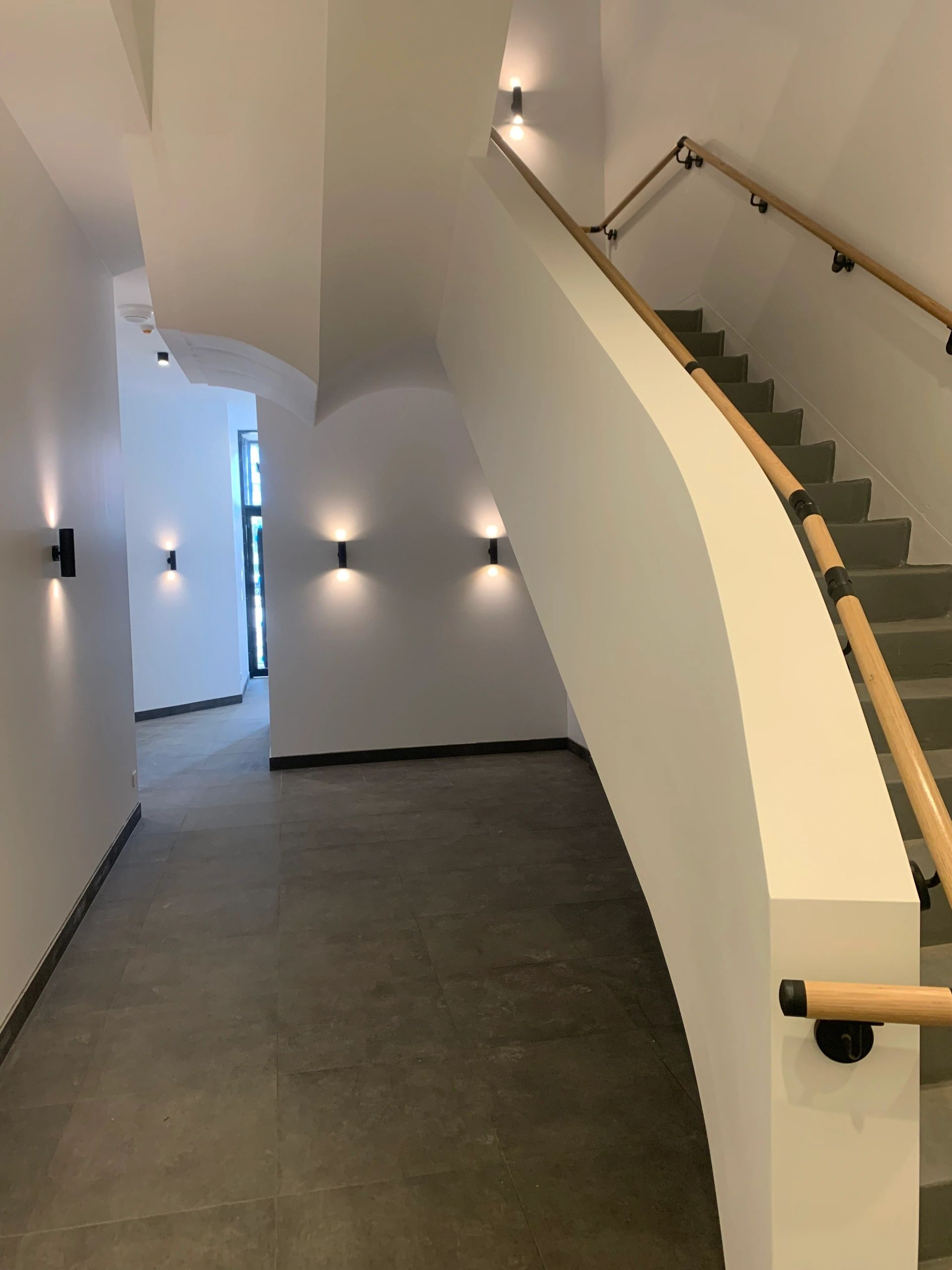 A curved staircase with a wooden railing in a hallway