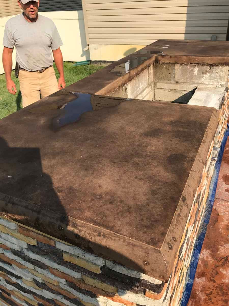 A man is standing on top of a concrete counter.