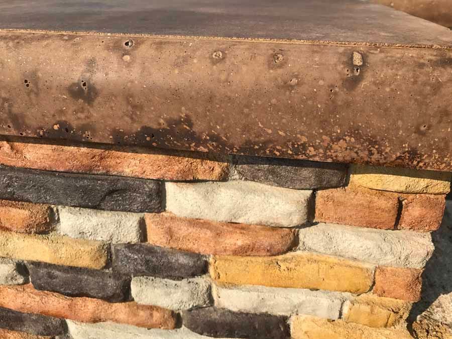 A close up of a brick wall with a concrete block in the middle.
