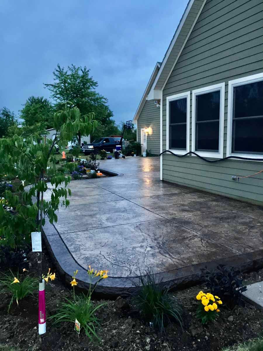 A house with a patio and flowers in front of it.