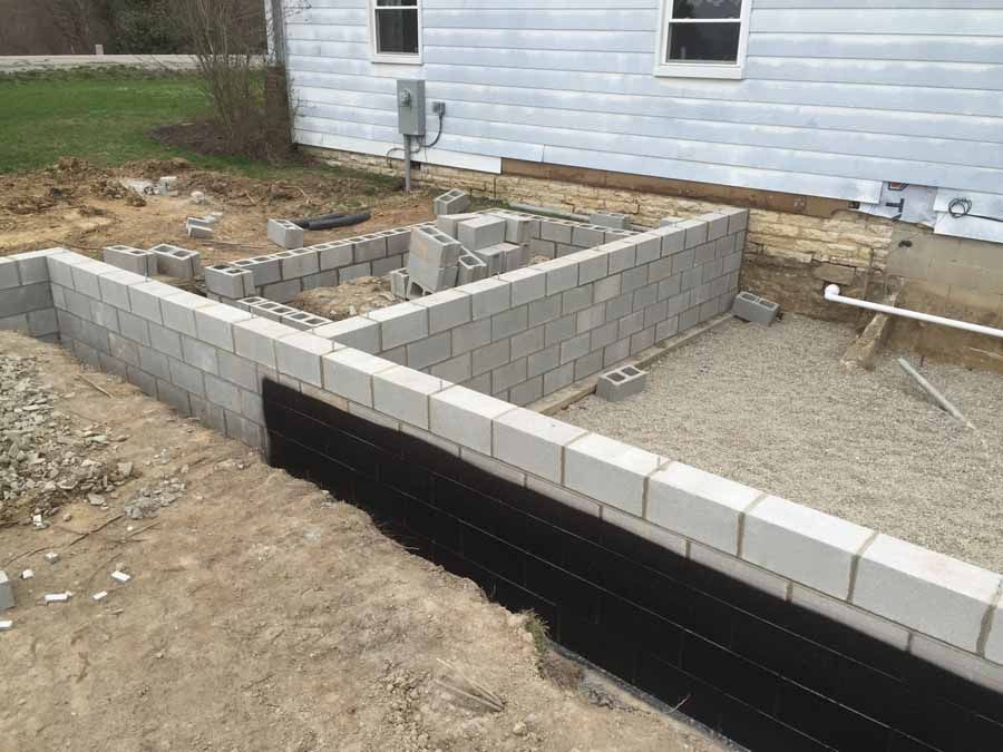 A brick wall is being built in front of a house.