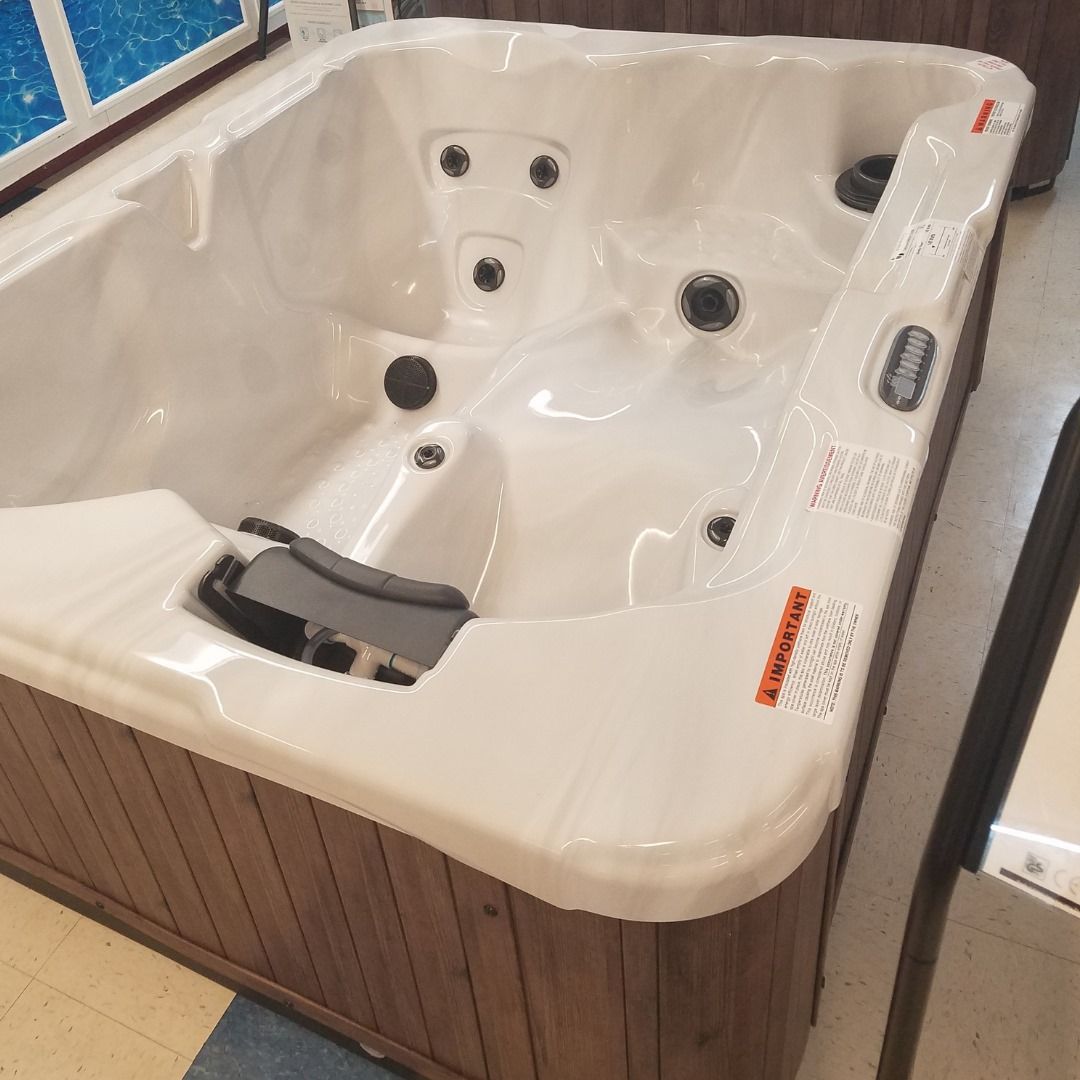 A white hot tub with a wooden base is sitting in a room.