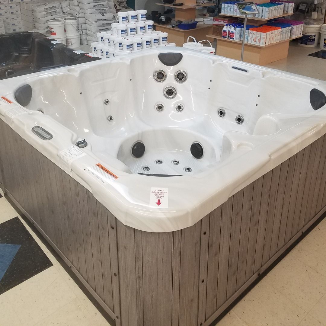 A white hot tub is sitting on a checkered floor in a store.