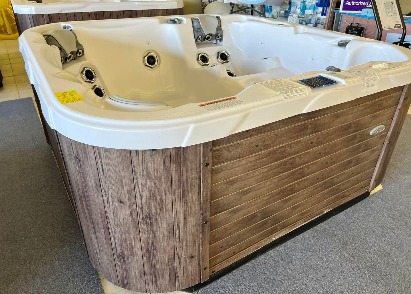 A white and wooden hot tub is sitting on a carpet in a store.