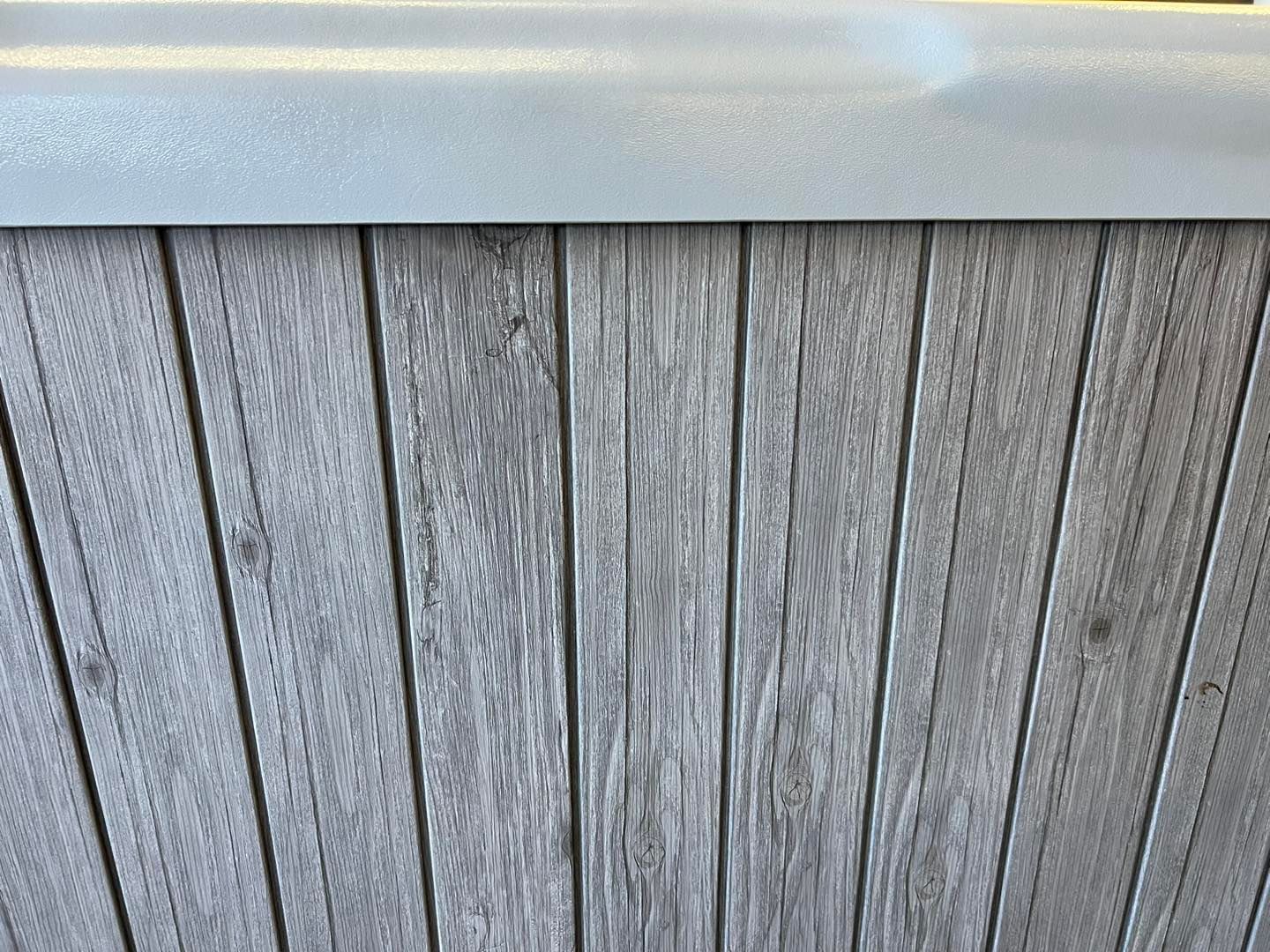 A close up of a wooden surface with a white trim.