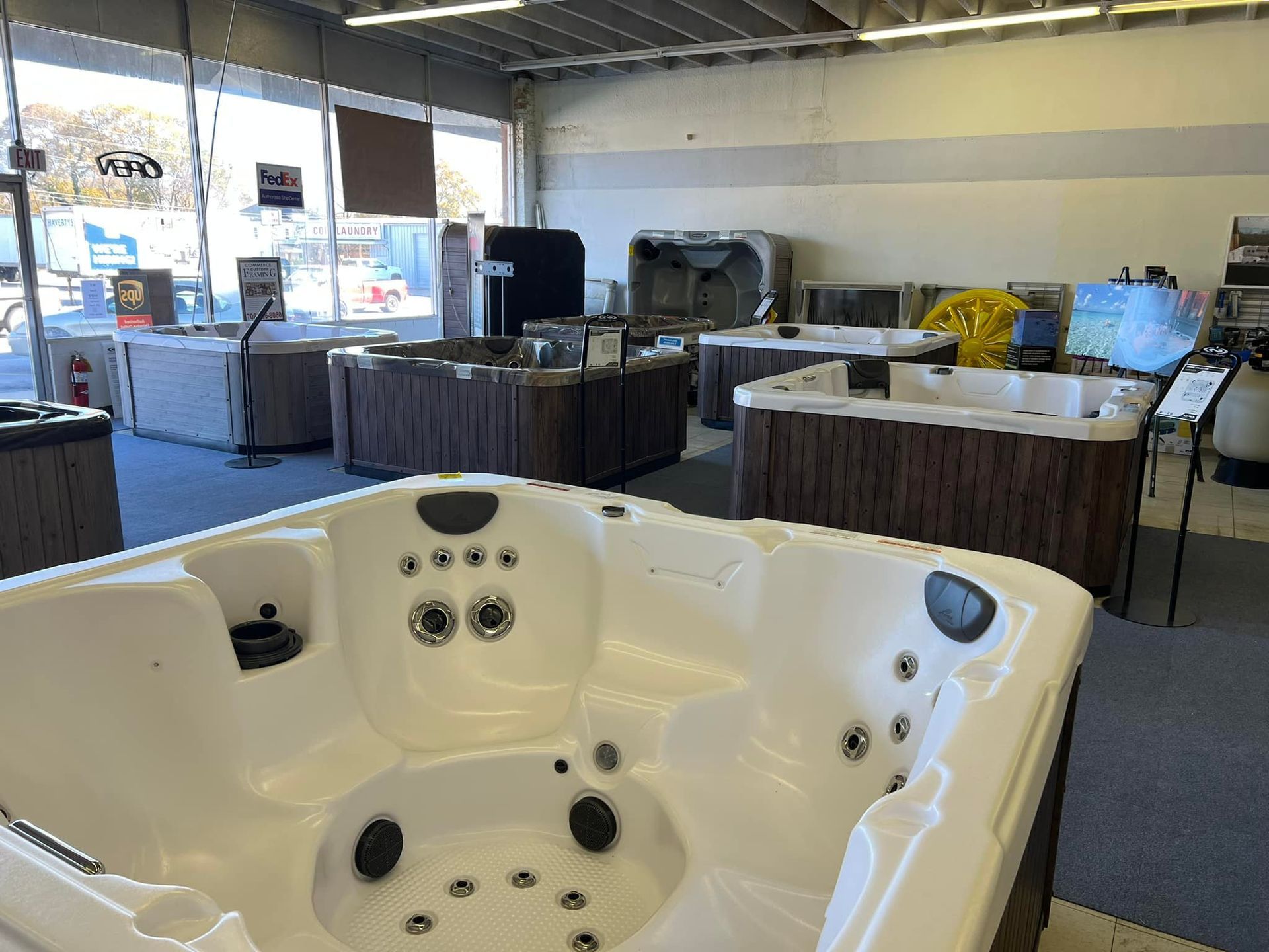 A white hot tub is sitting in a store surrounded by other hot tubs.