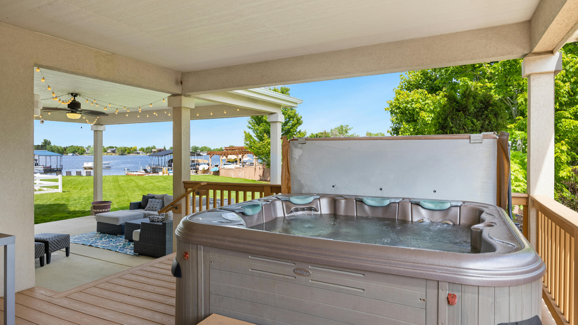 A hot tub is sitting on a porch next to a lake.