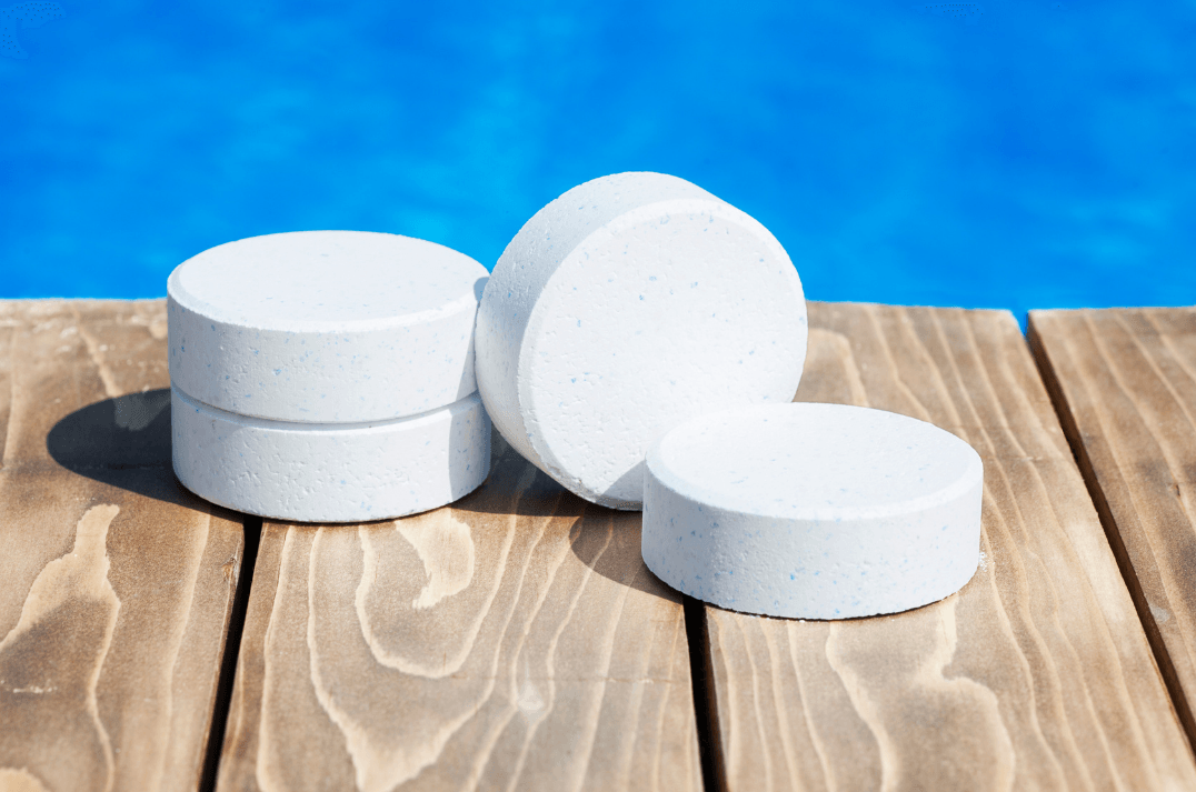 Four white tablets are stacked on top of each other on a wooden deck next to a swimming pool.
