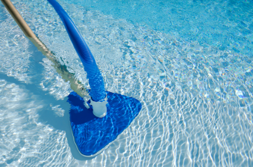 A blue vacuum cleaner is being used to clean a swimming pool.
