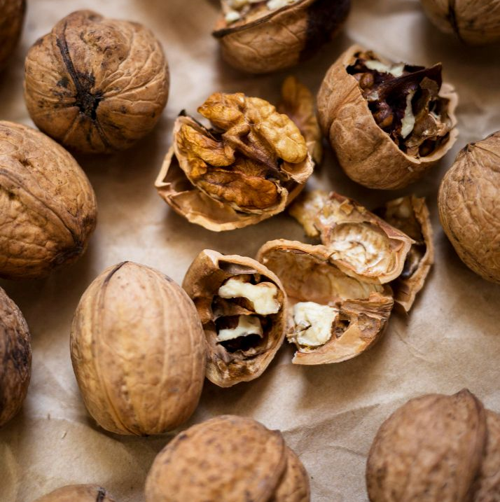 Nueces, algunas abiertas, esparcidas sobre papel marrón.