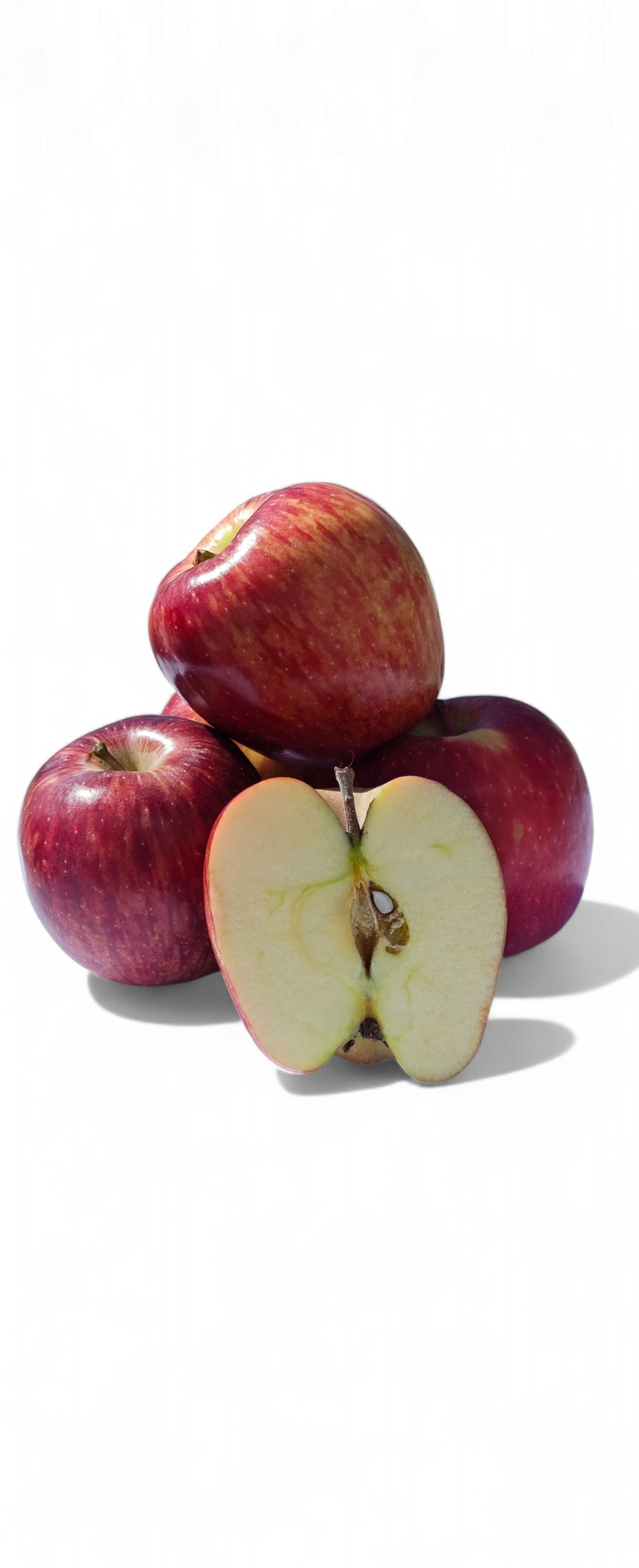 Pila de manzanas rojas, una de ellas cortada para revelar la pulpa, sobre una superficie blanca.