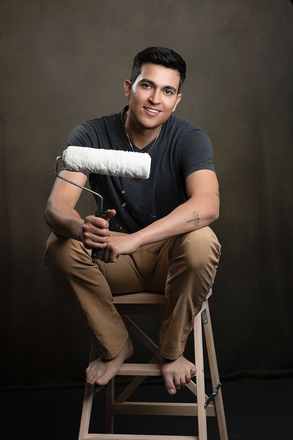 Home interior Painter holding a rolling brush, sitting on stairs