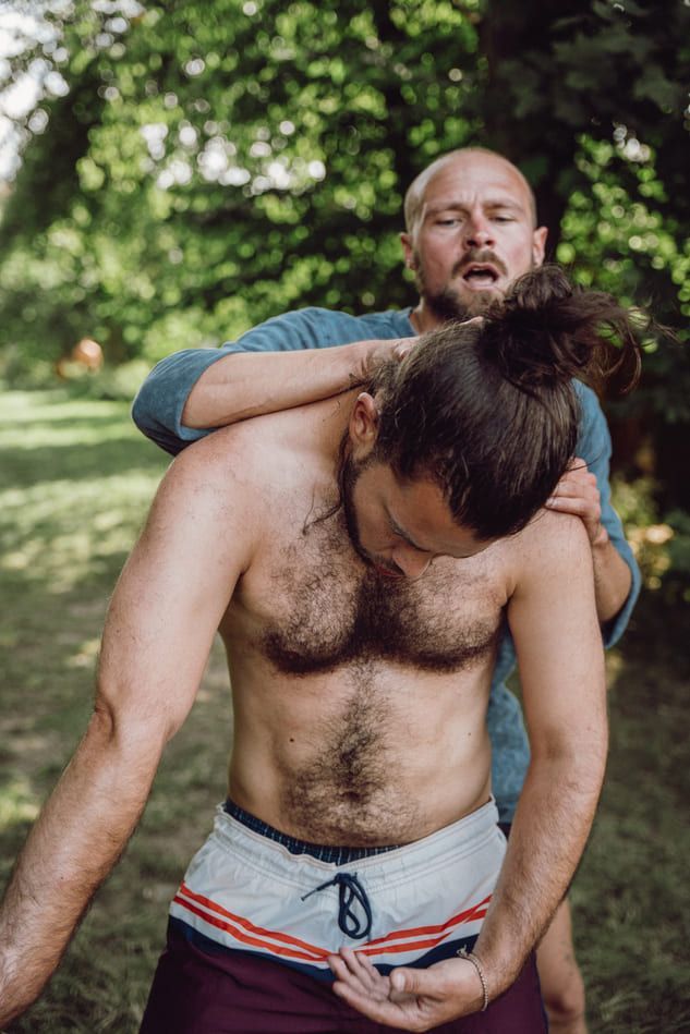 A man is being supported in a somatic dance in nature.