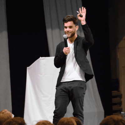 a man is standing on a stage holding a microphone in front of a crowd .