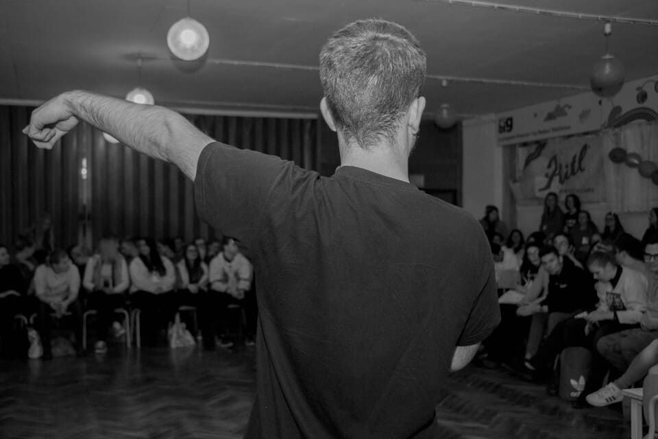 A man is standing in front of a crowd of people in a black and white photo.