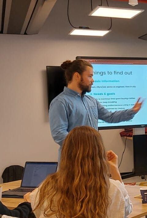 A man is giving a presentation in front of a screen that says things to find out