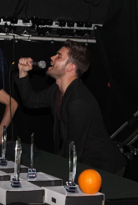 A man singing into a microphone next to an orange