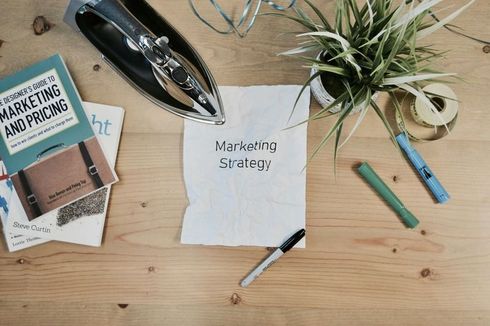 a wooden table with a piece of paper that says marketing strategy on it .