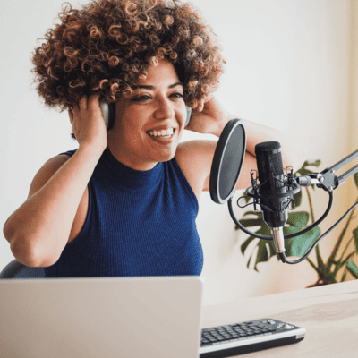 A woman wearing headphones is sitting in front of a microphone.