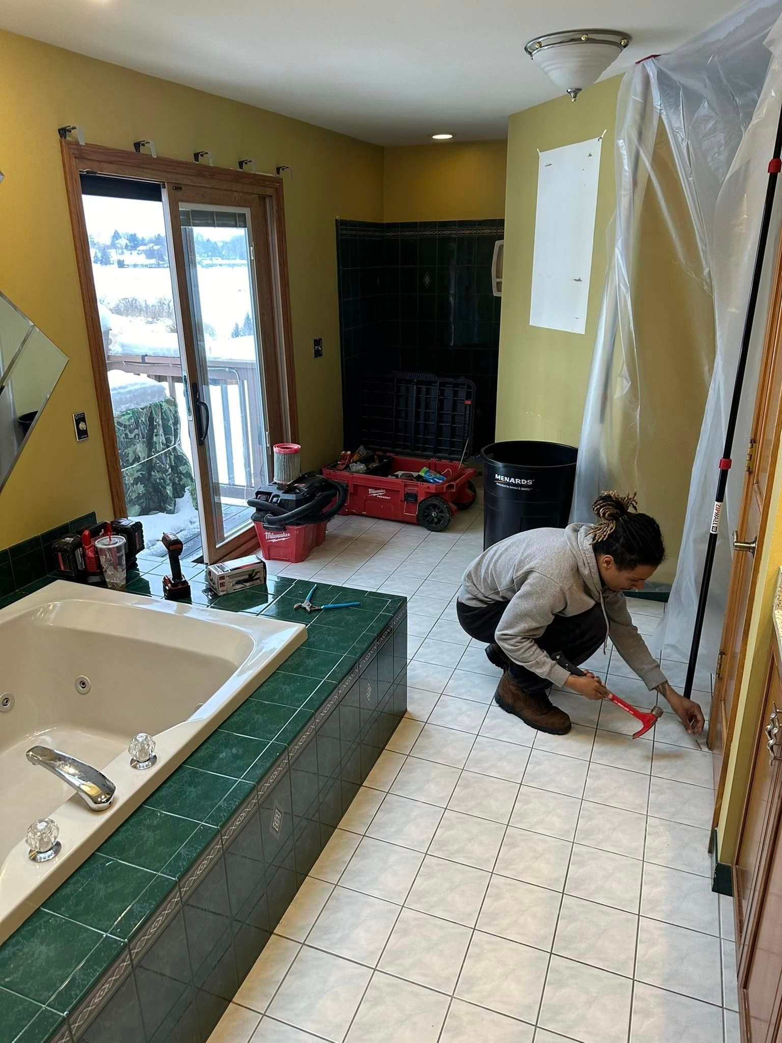 a man is kneeling down in a bathroom next to a bathtub .
