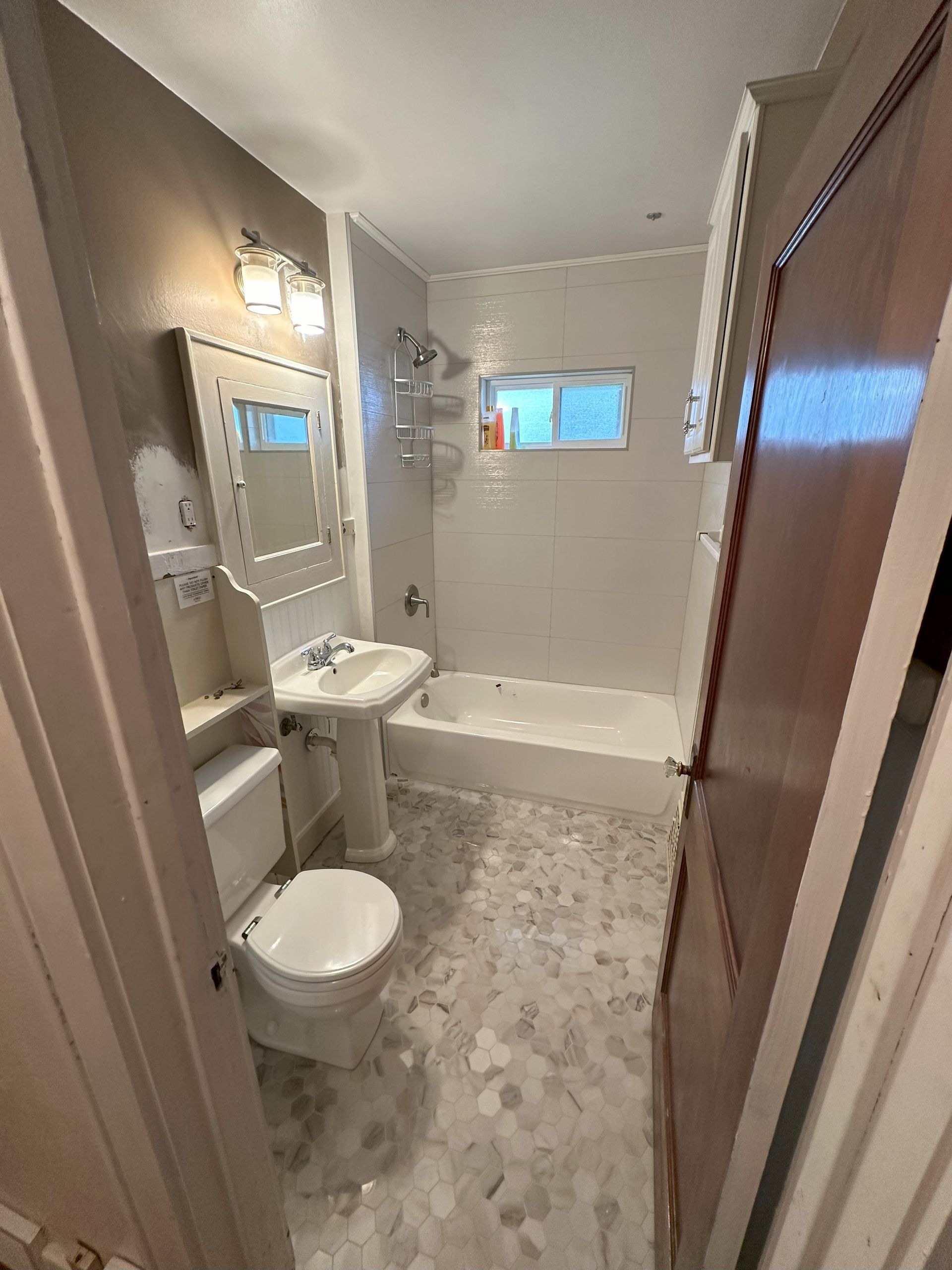 a bathroom with a toilet , sink , tub and mirror .