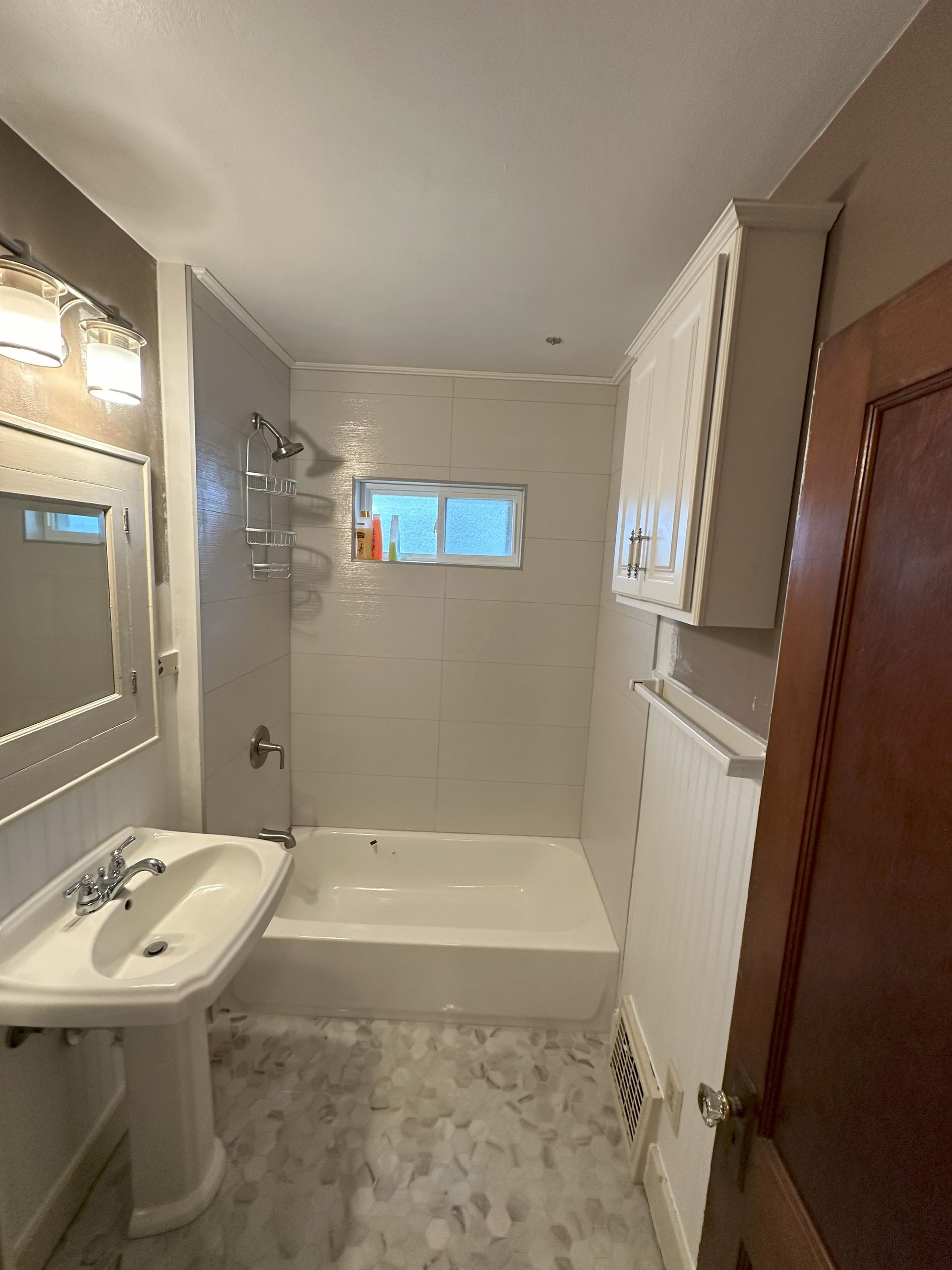 a bathroom with a sink , tub , mirror and window .