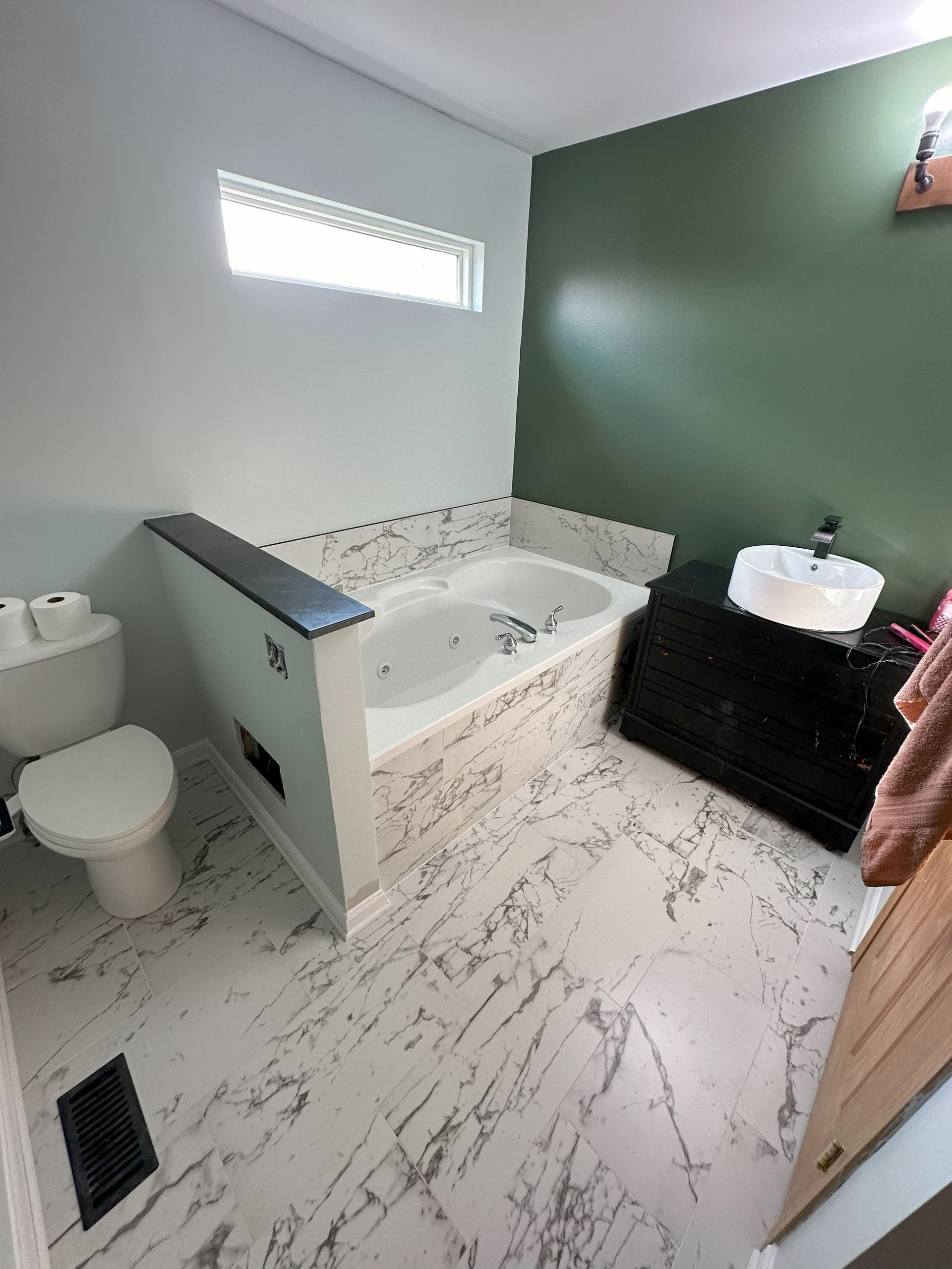 a bathroom with a tub , toilet , sink and window .