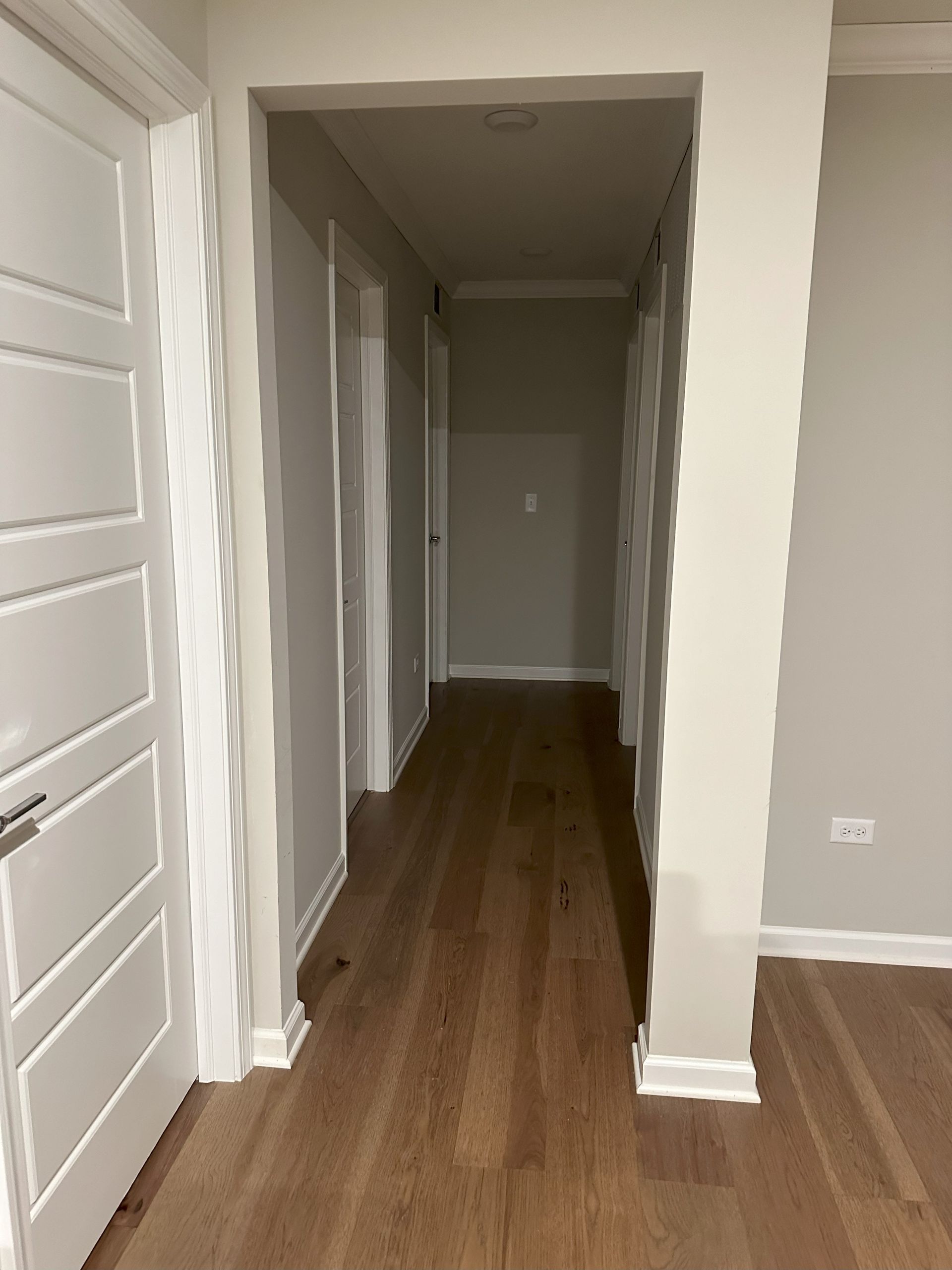 an empty hallway with hardwood floors and white doors