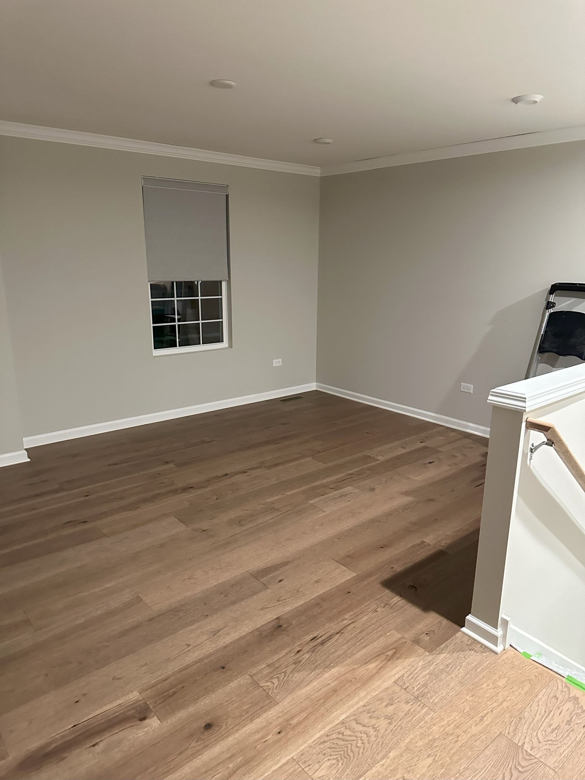 an empty living room with hardwood floors and a window .
