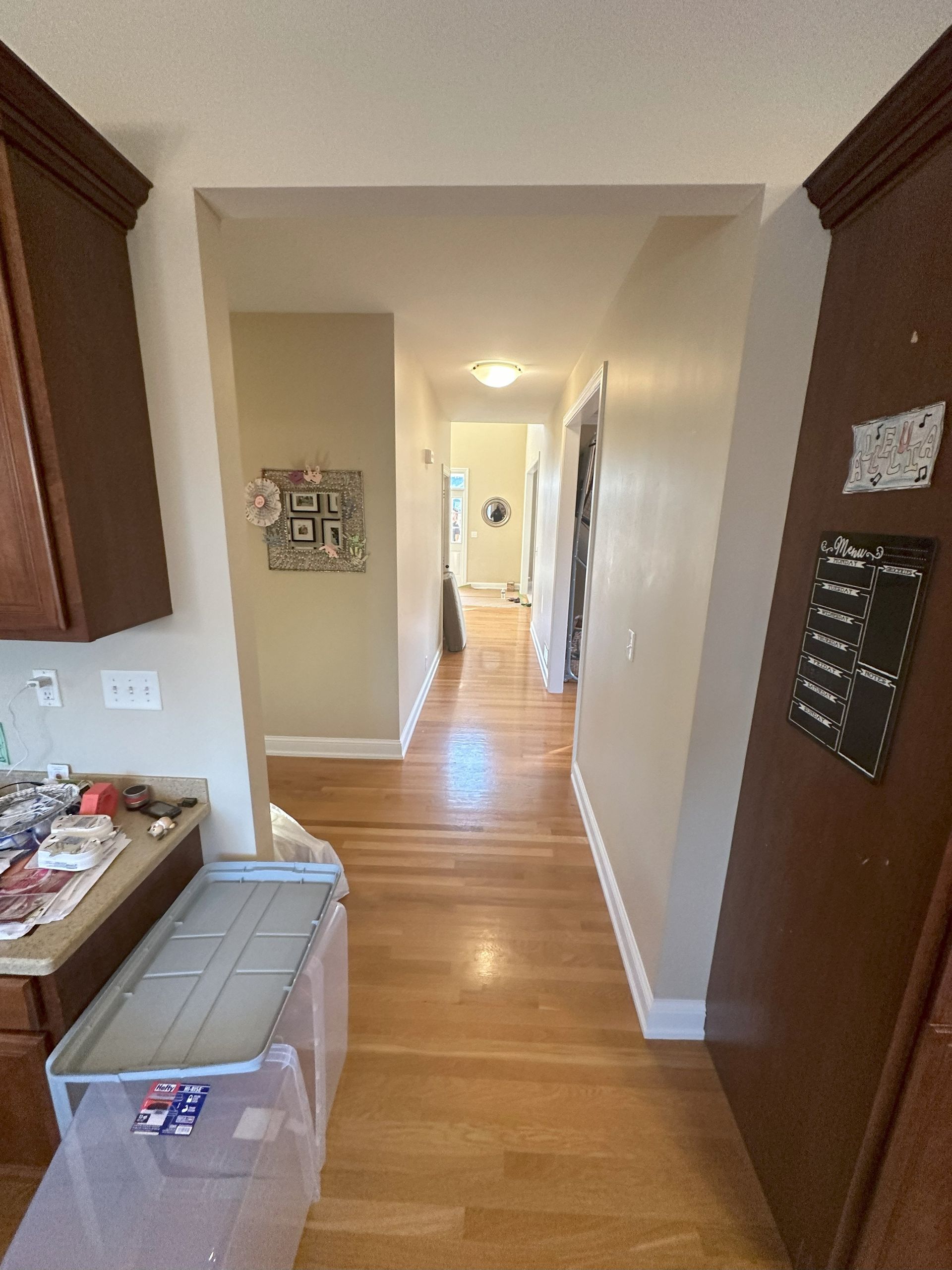a hallway in a house with hardwood floors leading to a kitchen .