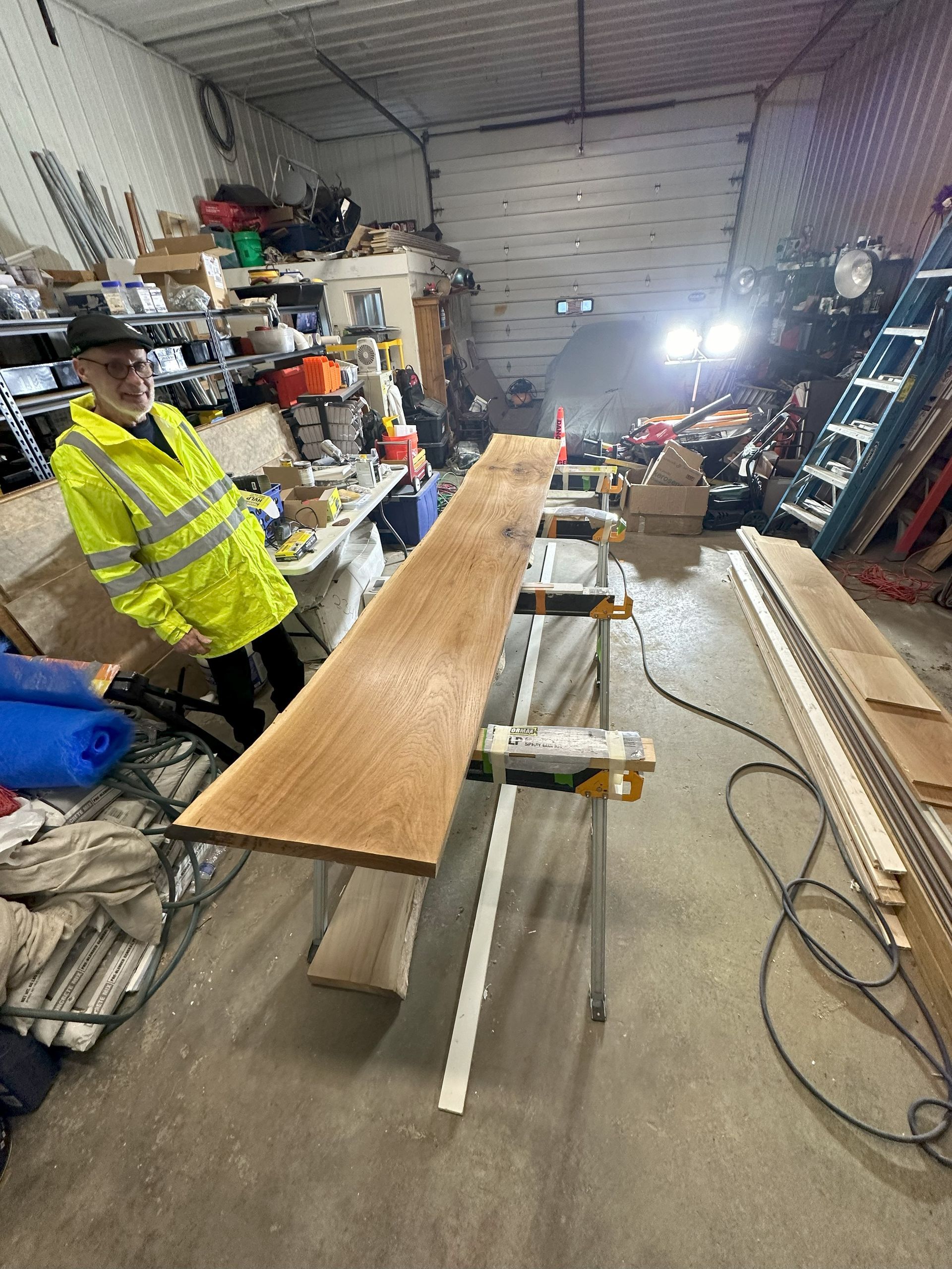 a man is standing next to a long piece of wood in a garage .