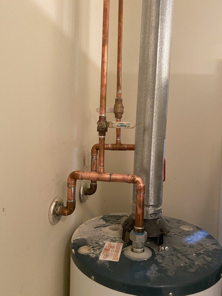 a close up of a water heater with copper pipes attached to it .
