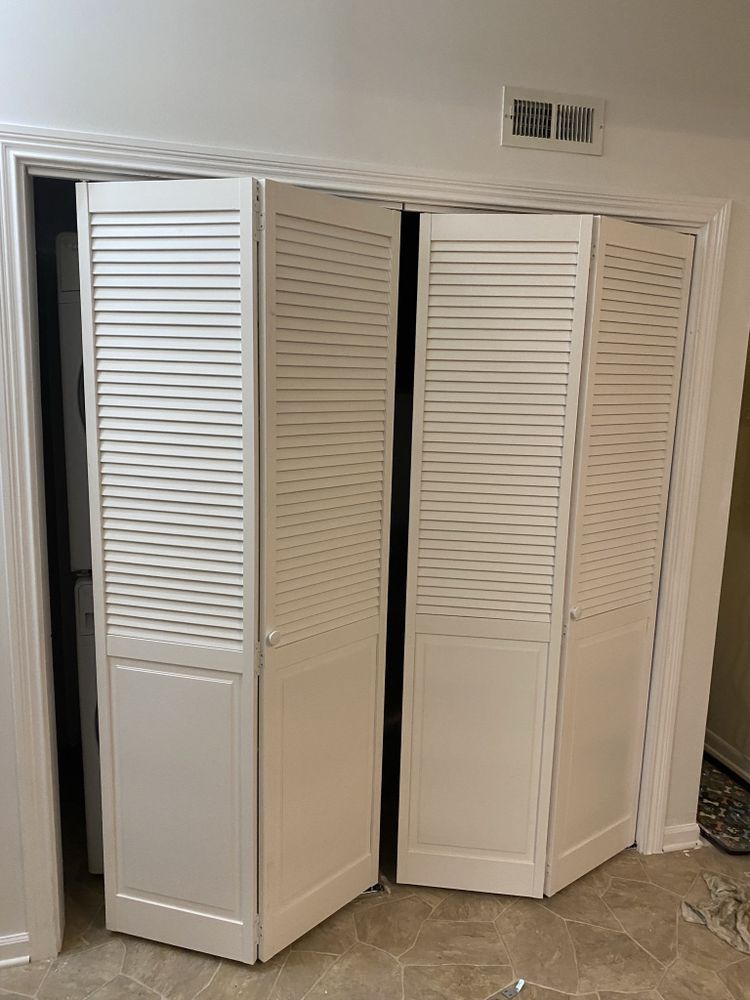 a pair of white louvered closet doors are open in a room .