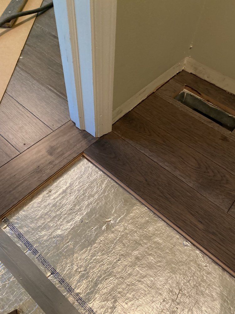 a wooden floor is being installed in a room next to a door .