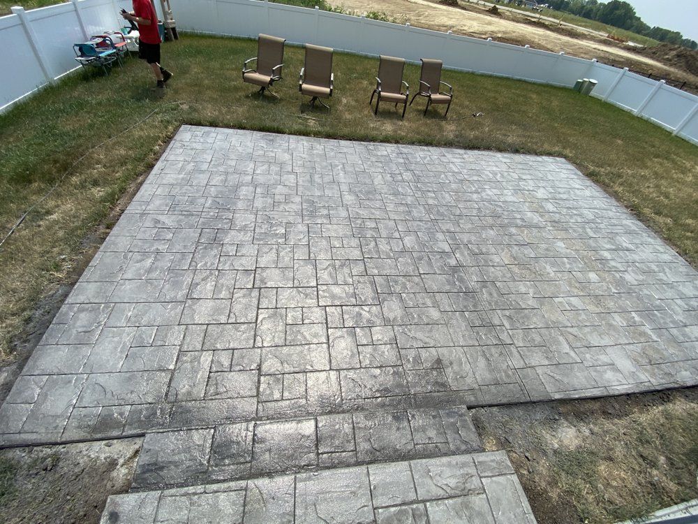 a concrete patio with chairs and stairs in a backyard .