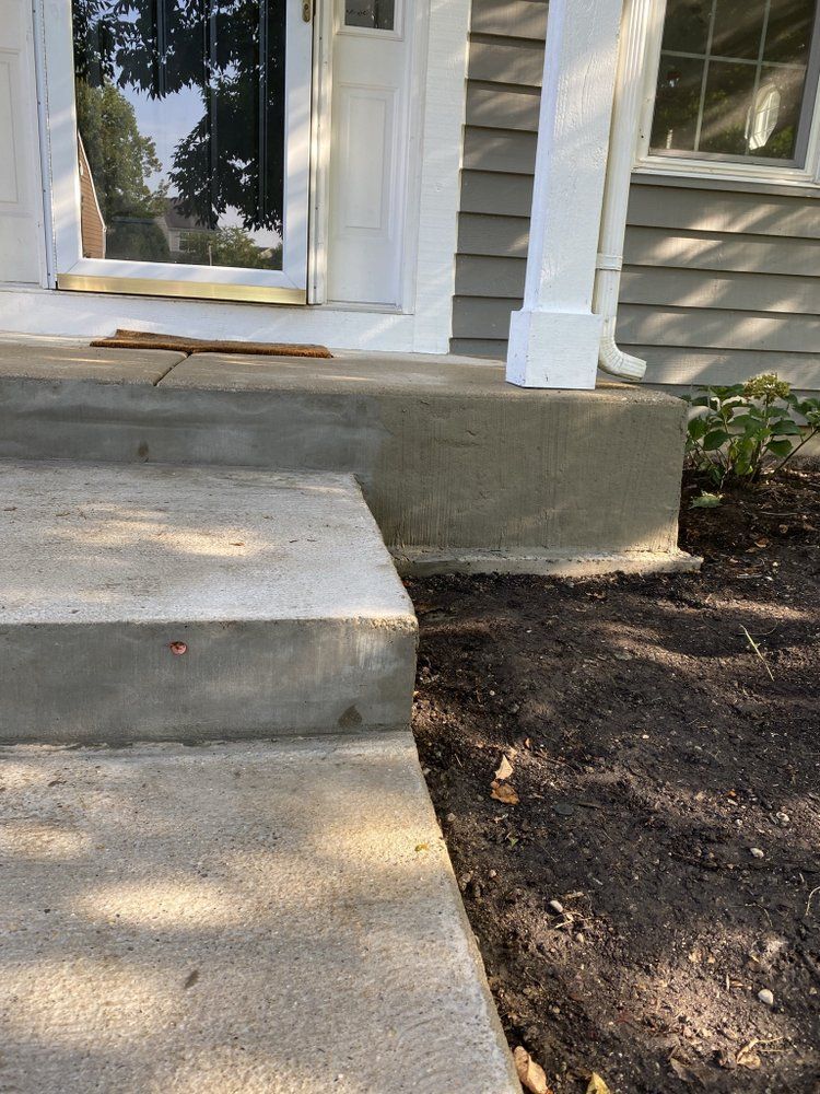a concrete walkway leading to a porch of a house
