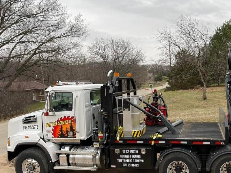 A dump truck with a flatbed is parked on the side of the road.
