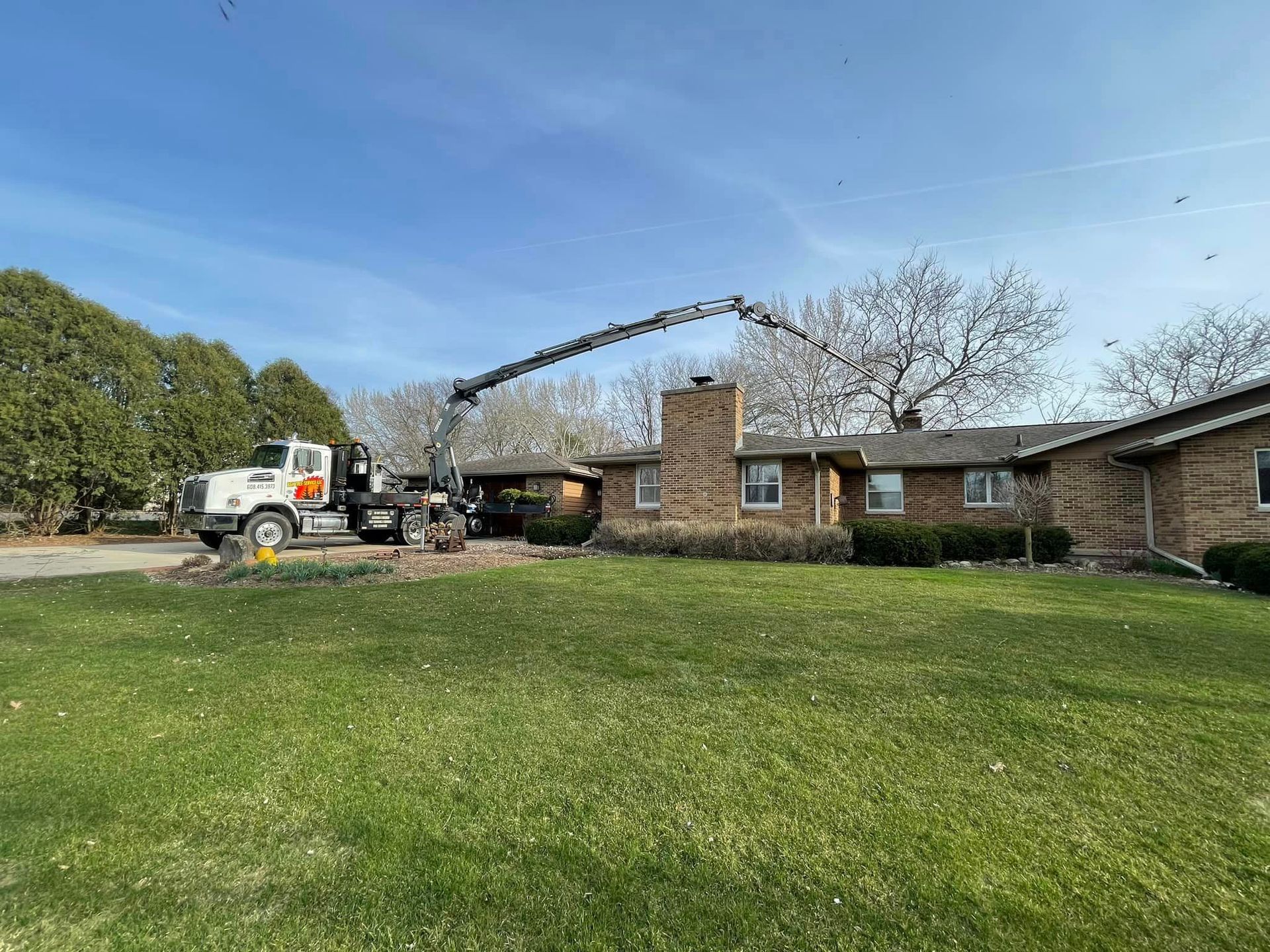 A truck is parked in front of a house with a crane attached to it.