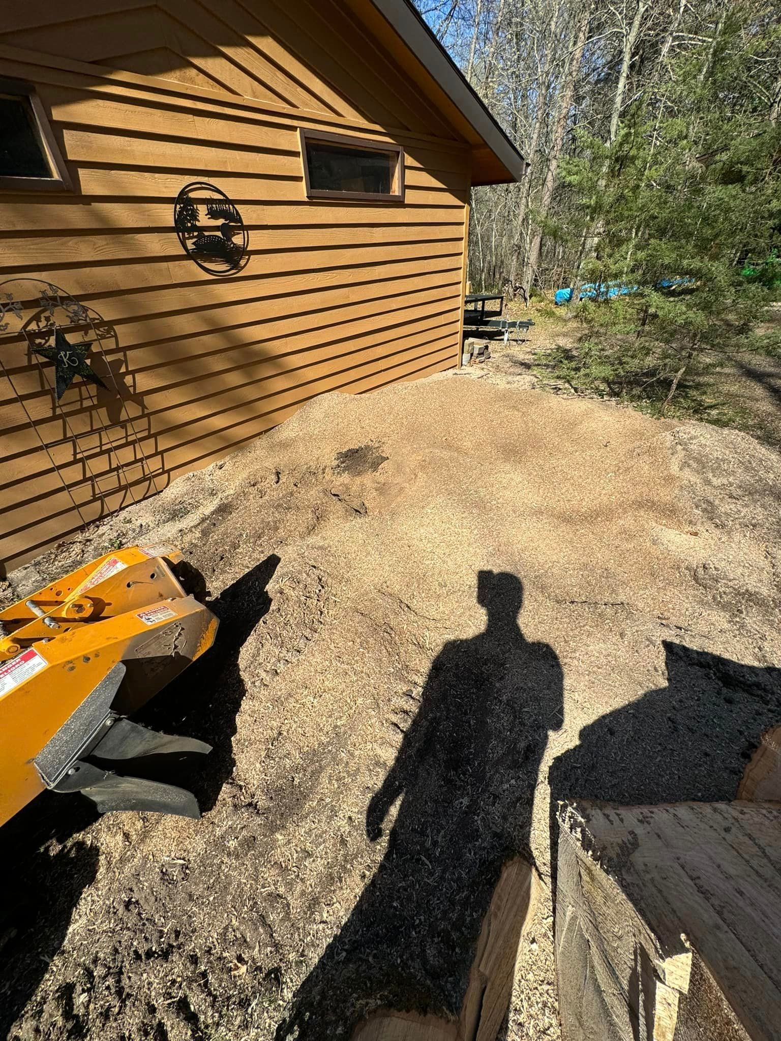 A stump grinder is being used to remove a tree stump in front of a house.