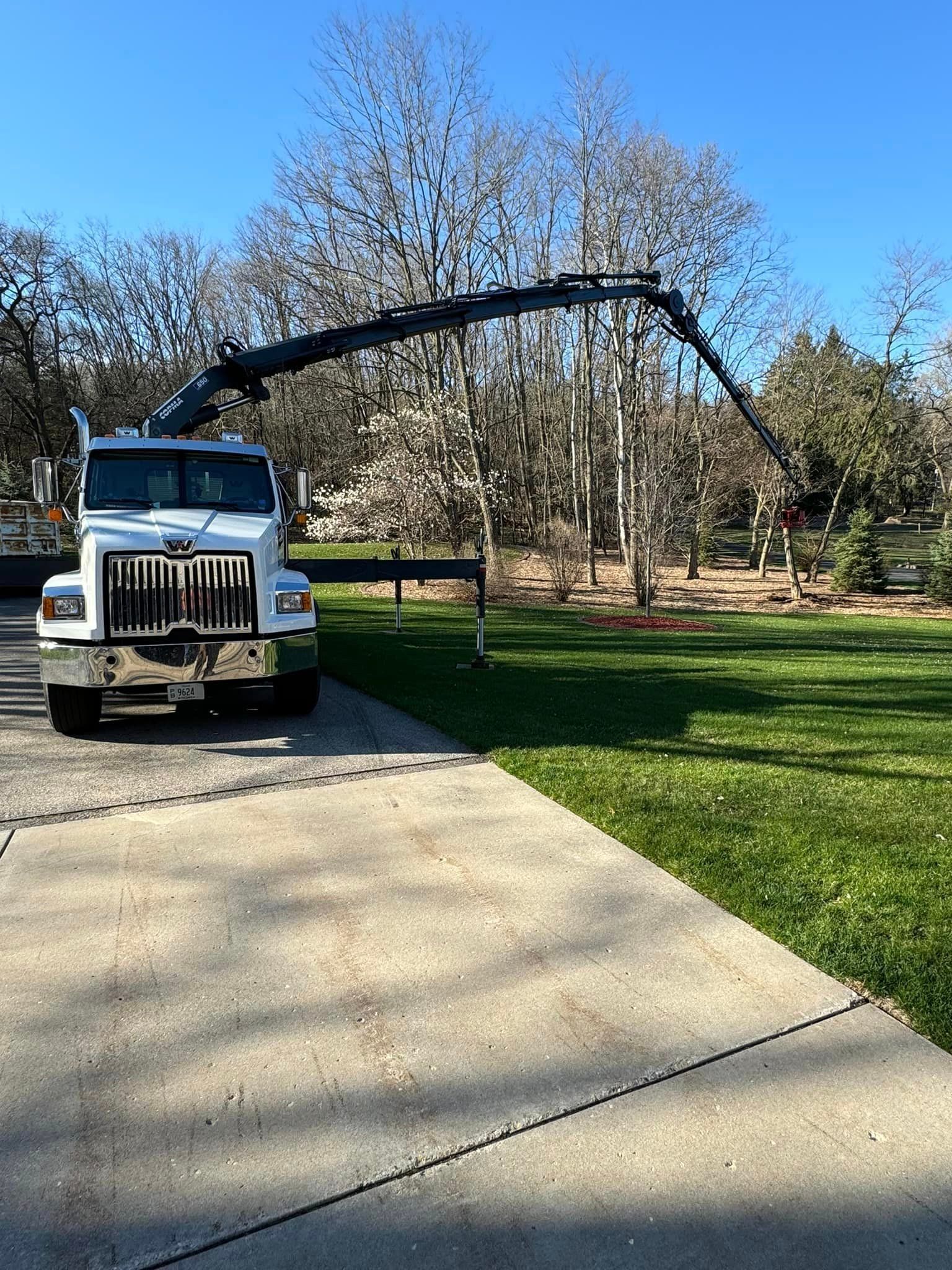 A white truck with a crane on the back is parked in a driveway.