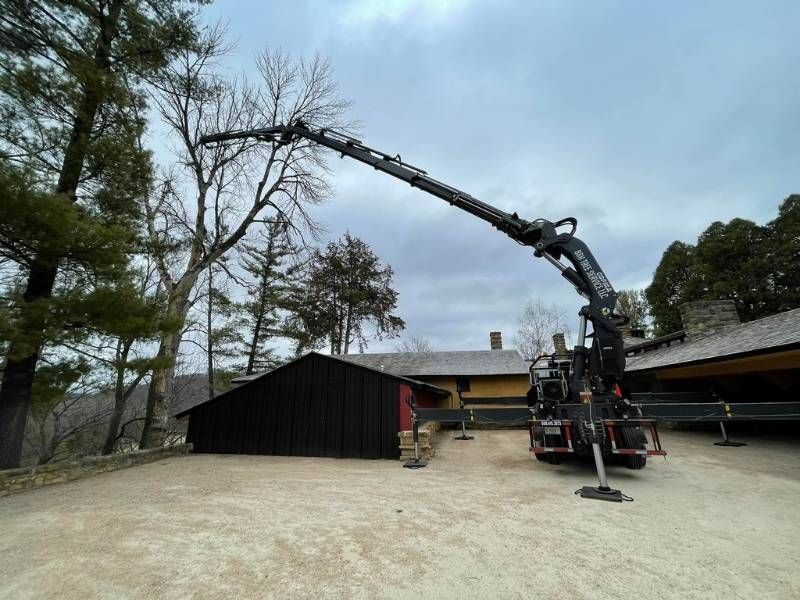 A truck with a crane attached to it is parked in front of a building.