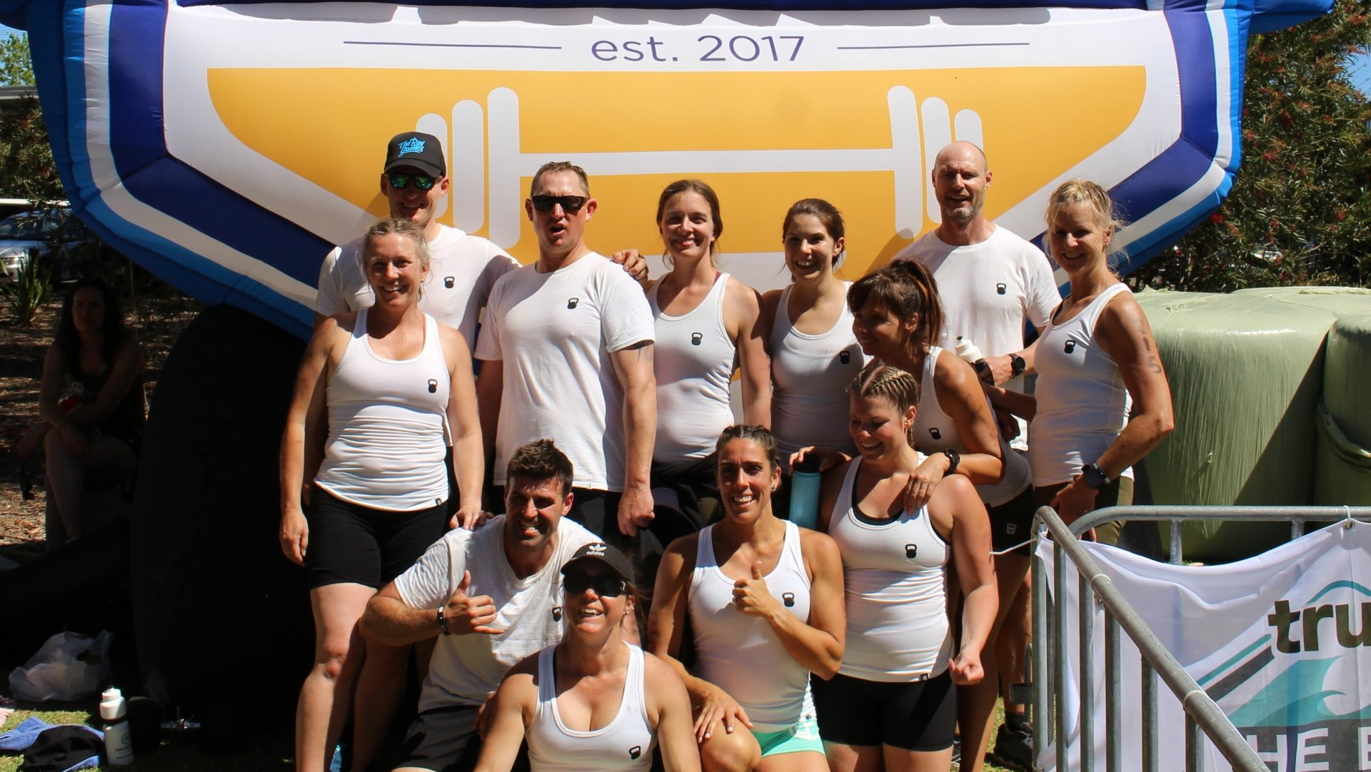 A group of people posing for a picture in front of an inflatable sign that says est 2017