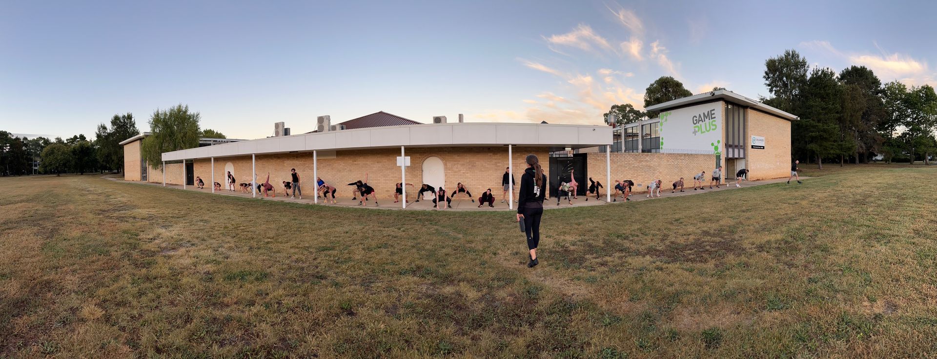 A person is standing in front of a large building in a field.